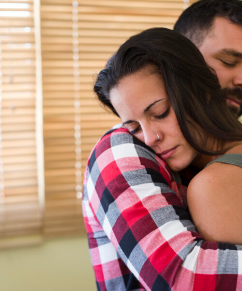Pareja abrazándose con ternura, transmitiendo apoyo emocional en un ambiente íntimo y cálido.
